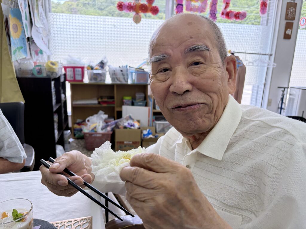 生春巻きの皮で作ったお花の飾りを手に取る男性のご利用者様